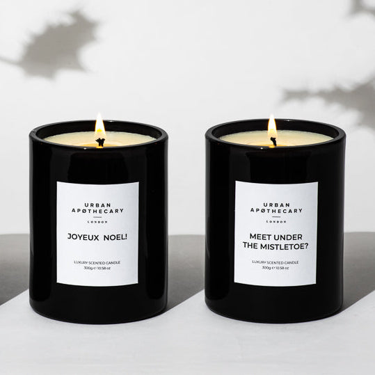 Two black candles with white labels on a light background